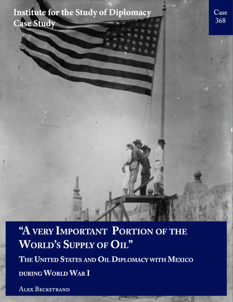 Archival black and white photograph of several soldiers standing beneath the U.S. flag.