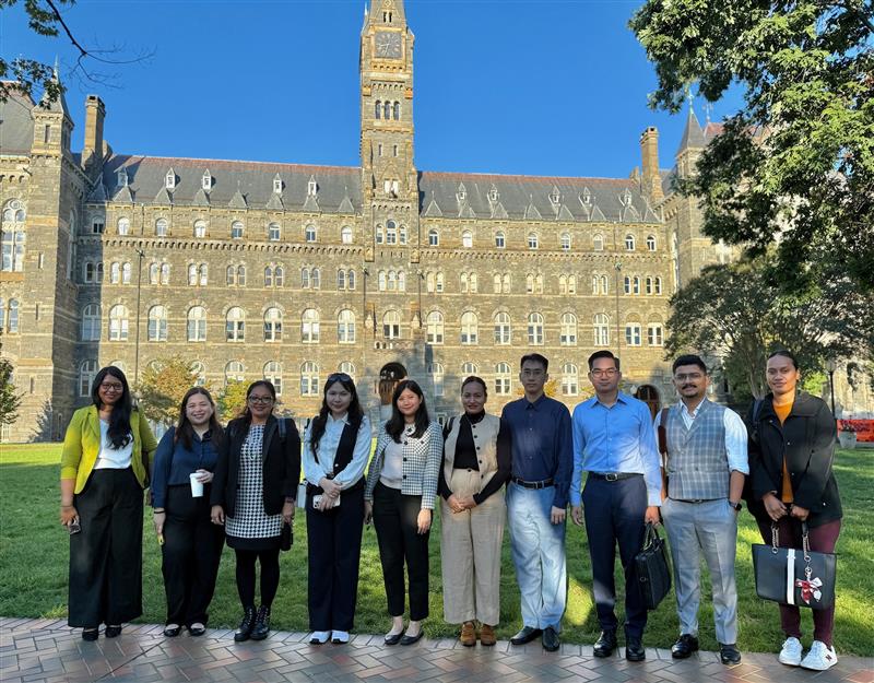 A group of students in front of a large church-like tower, the main building of Georgetown University