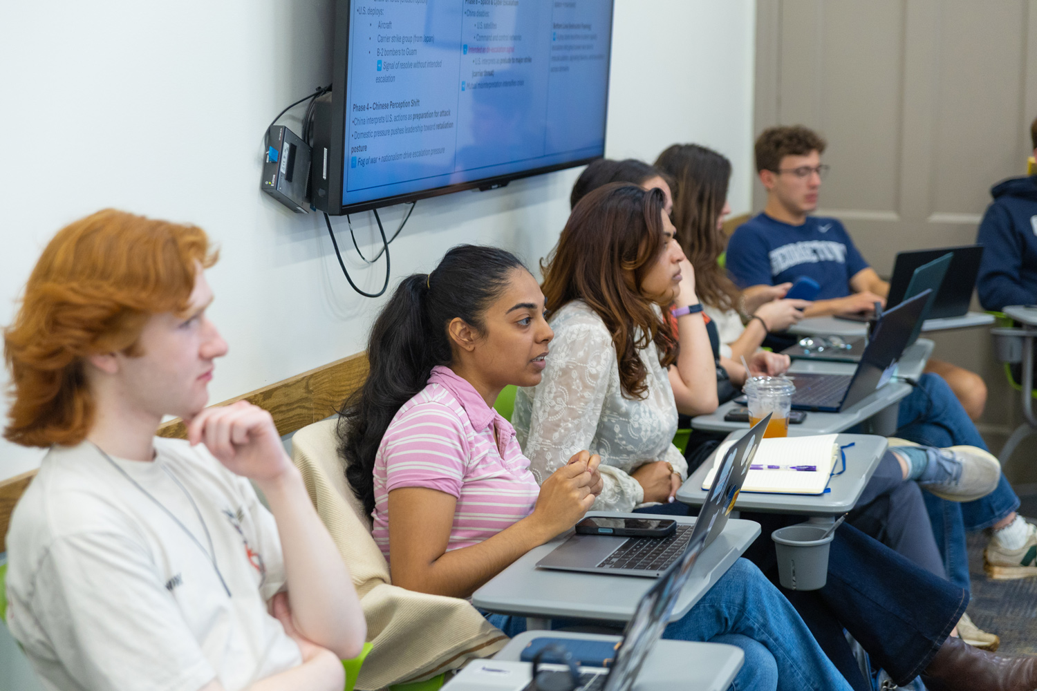 Students in class arranged in a semi-circle participating in discussion