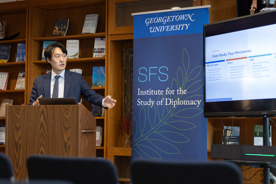 Man speaking from a podium, presenting slides on a screen
