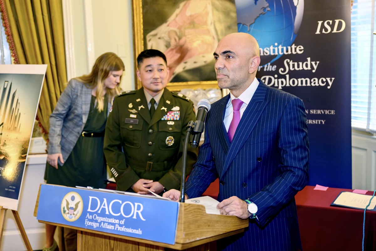 Speaker at podium next to fellow in military uniform