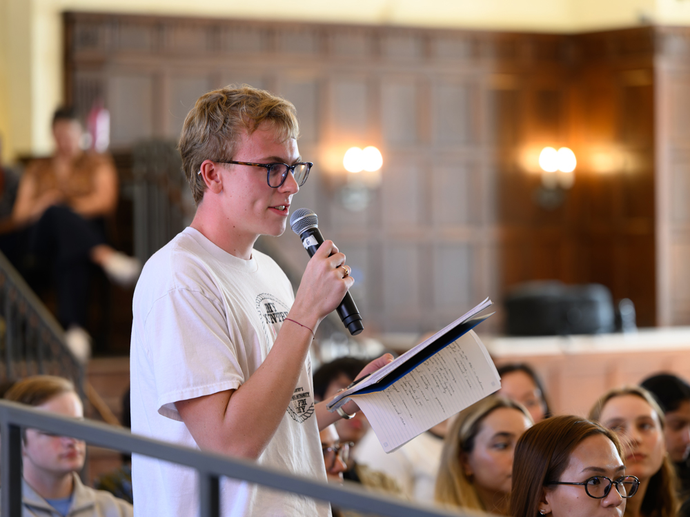 Student asking a question while holding a notebook
