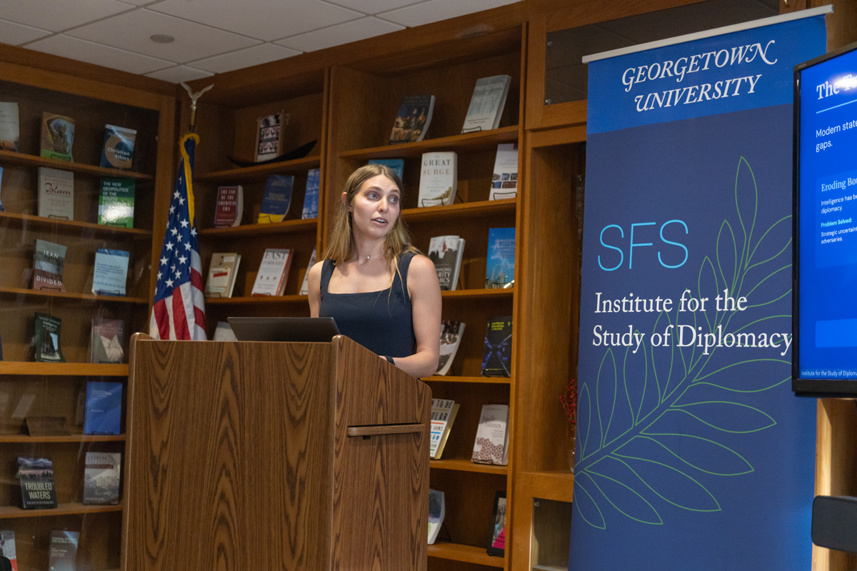 Student presenting at podium next to ISD banner