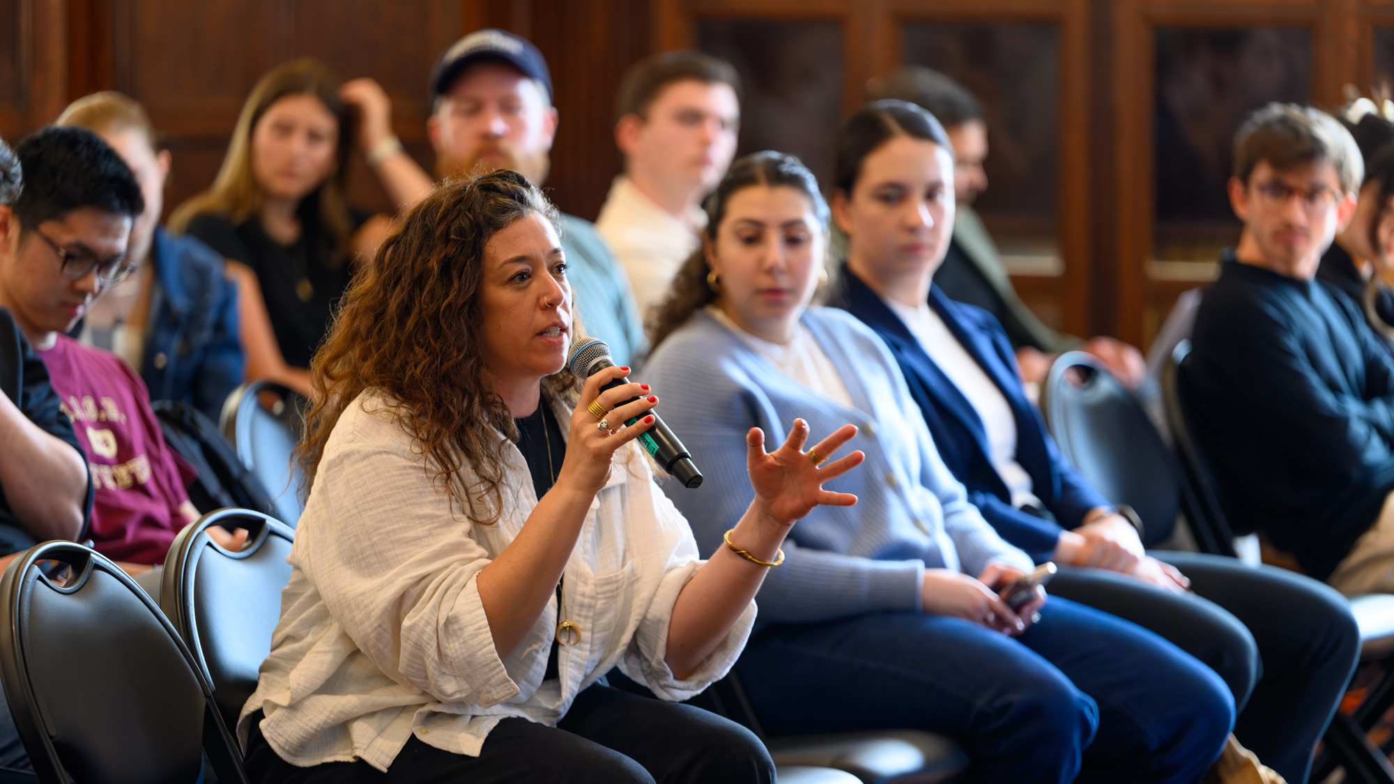 Student holding a microphone as part of an event audience